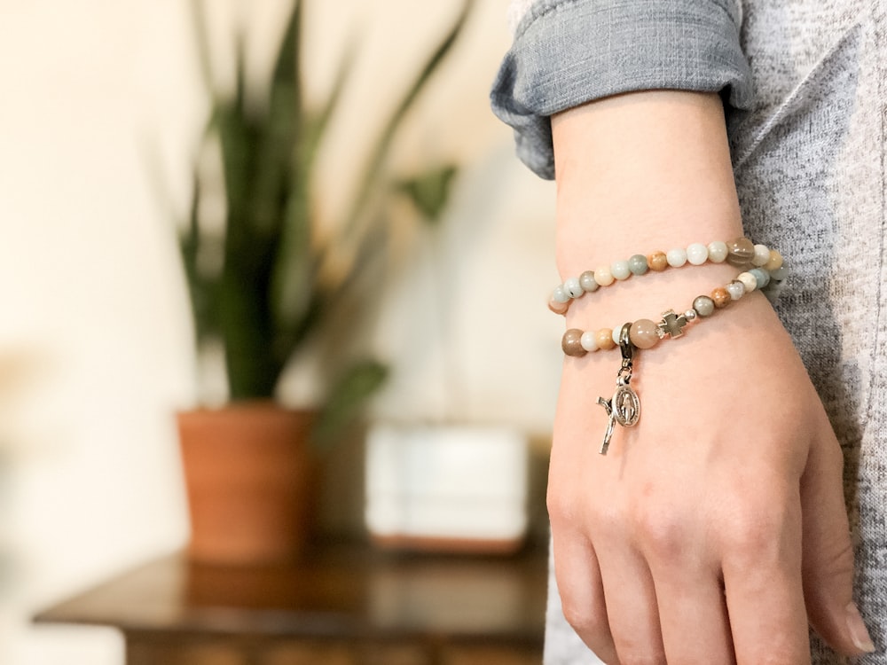 a woman wearing a bracelet with a cross charm