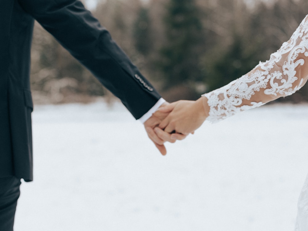 a bride and groom holding hands in the snow