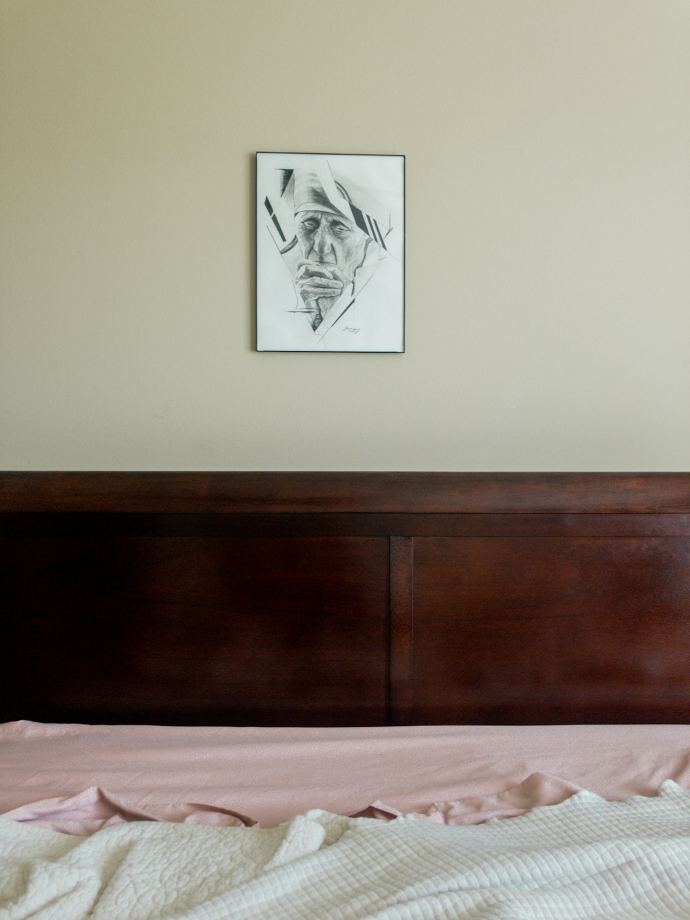 a bed with a pink comforter and a picture on the wall