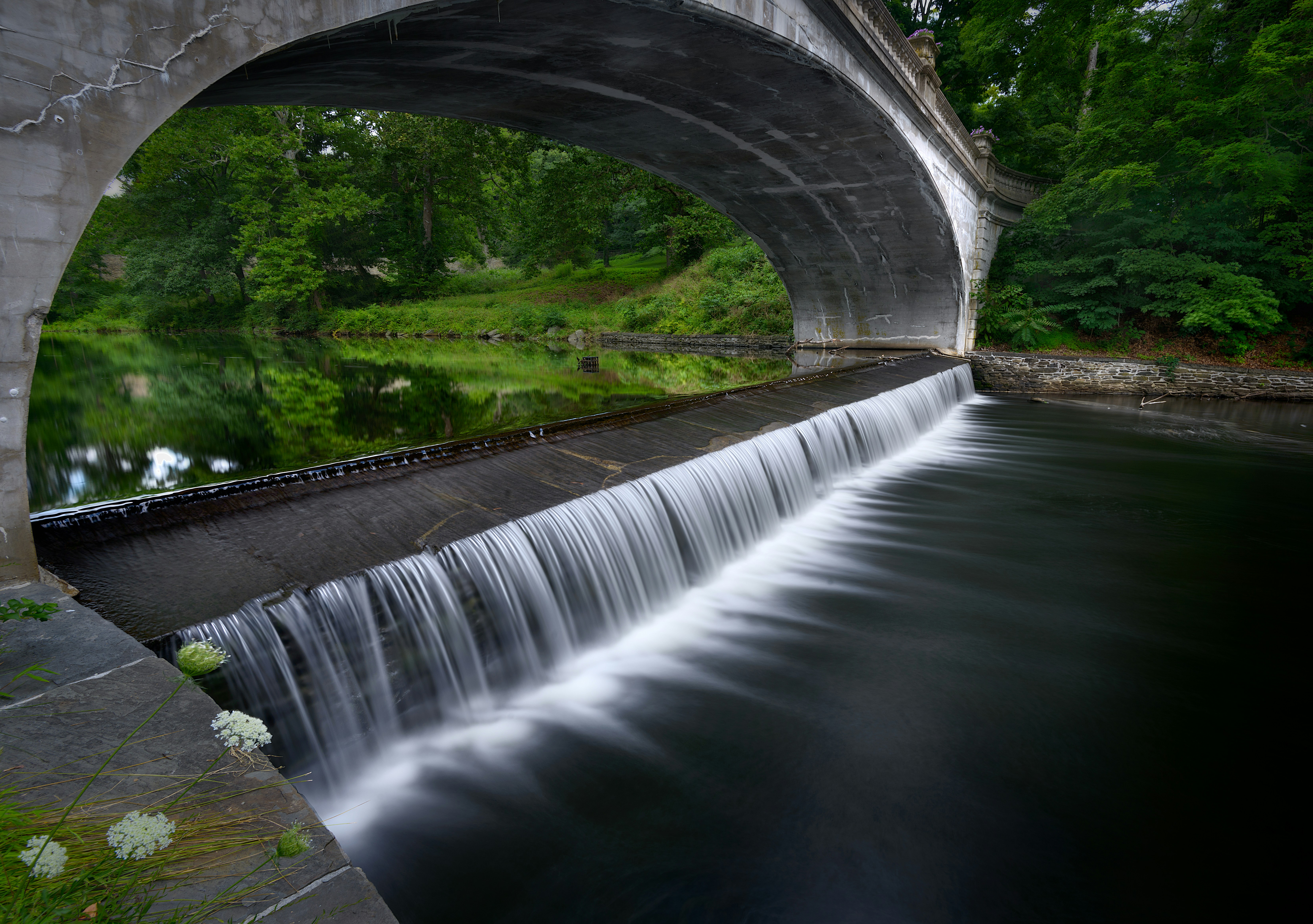 a bridge over a river with a waterfall under it
