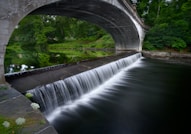 a bridge over a river with a waterfall under it