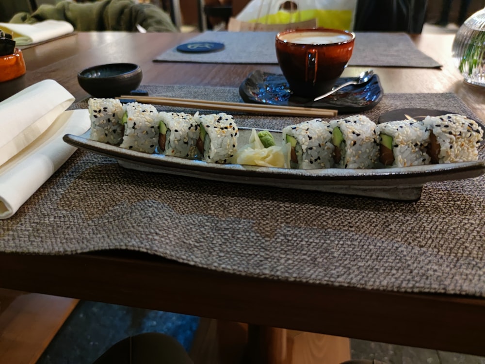 a plate of sushi and chopsticks on a table