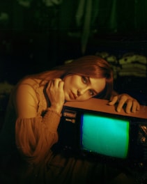 a woman leaning on a tv with a green screen