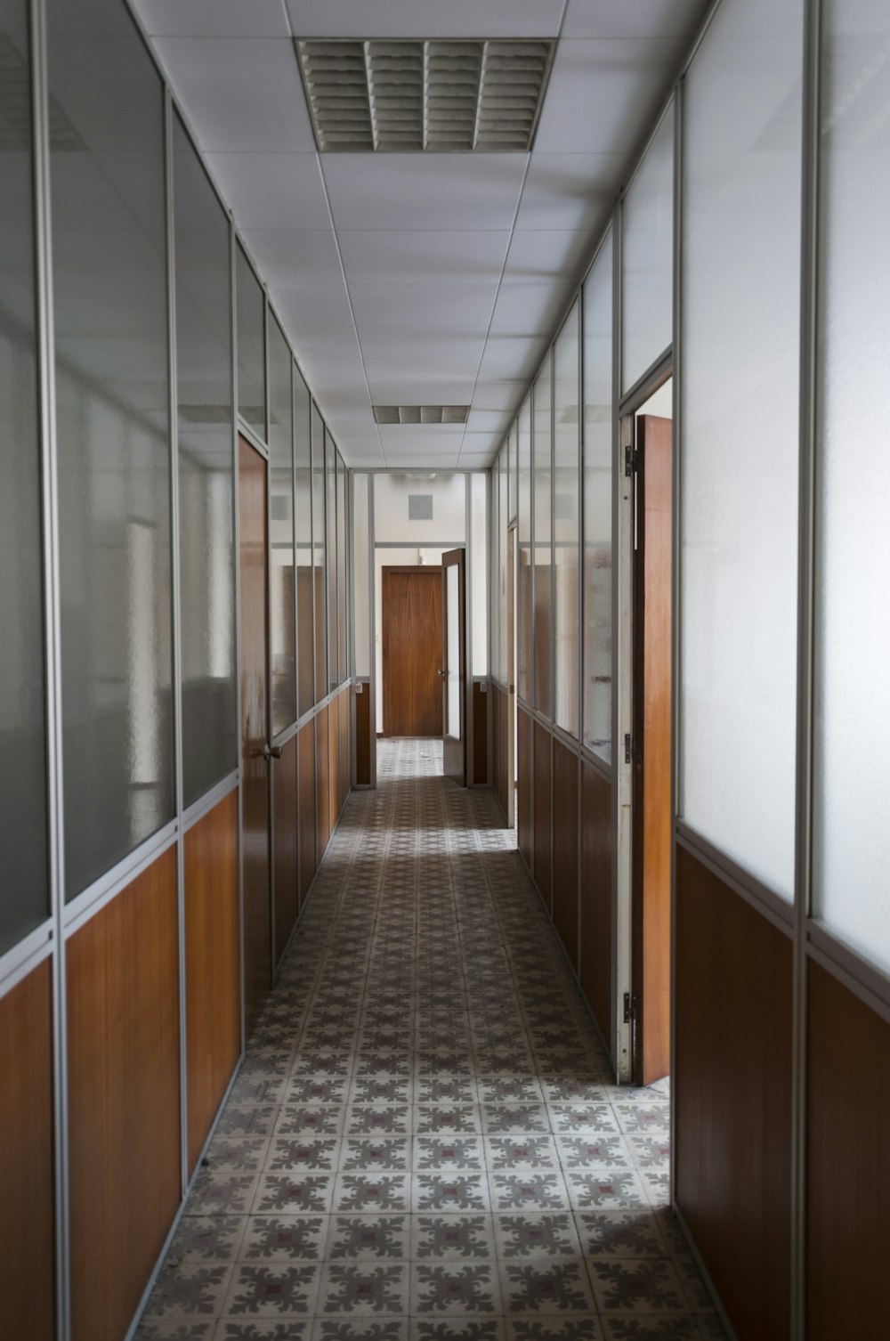 a long hallway with a tiled floor and wooden doors