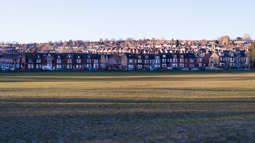 a field with a bunch of buildings in the background