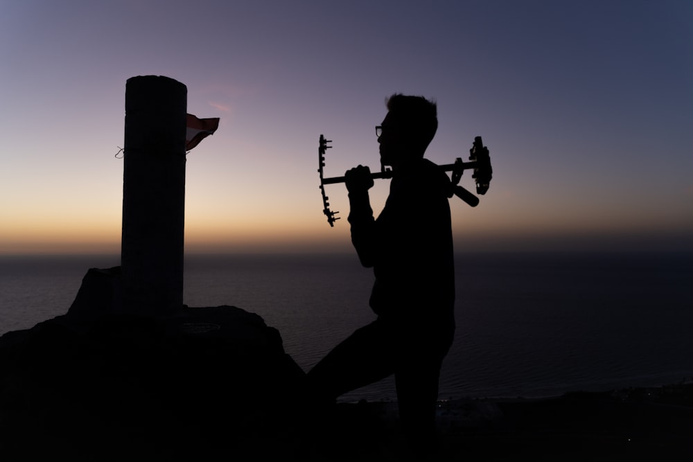 a man holding a violin while standing next to a cross