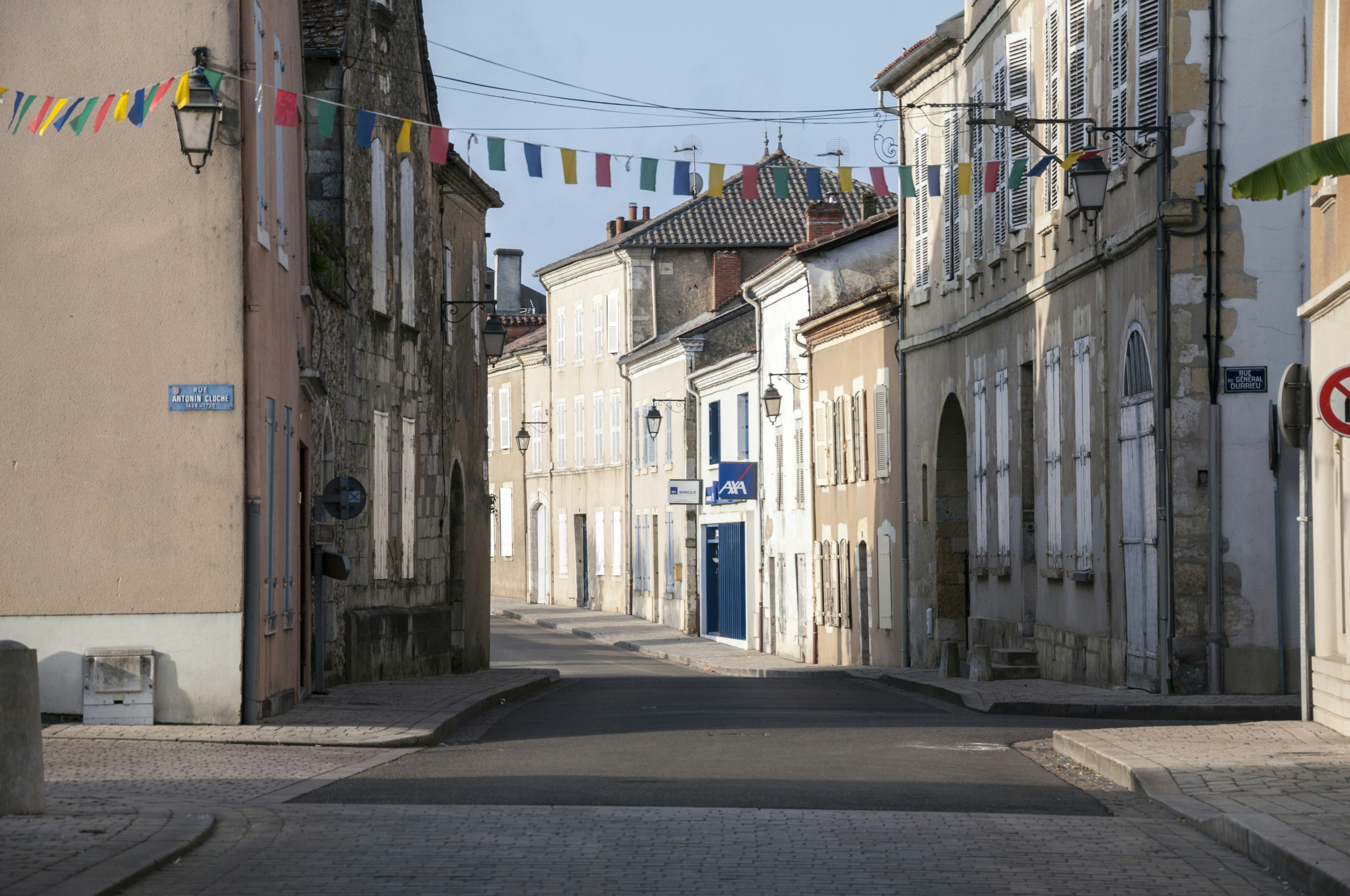 Una calle estrecha bordeada de edificios y banderas