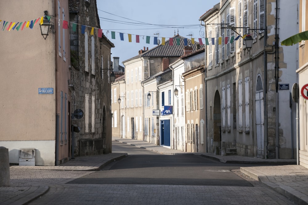 a narrow street lined with buildings and flags