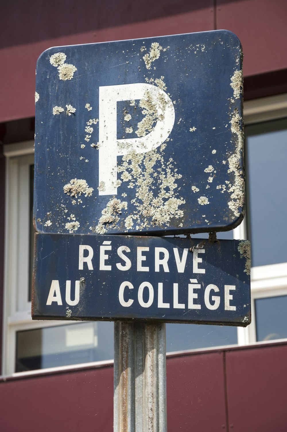 a rusted parking sign in front of a building