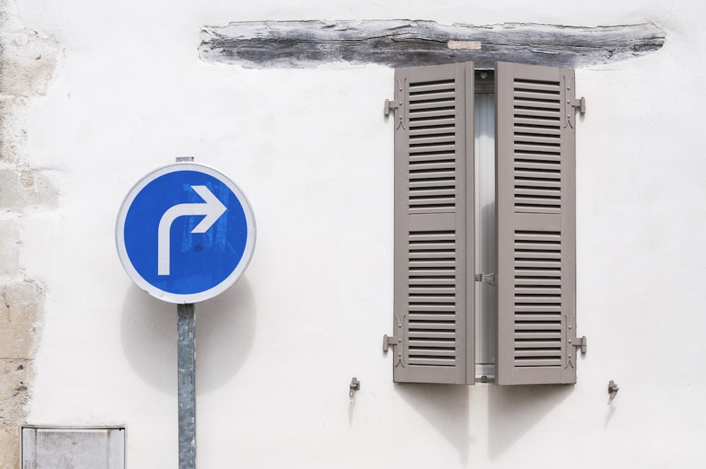 a blue and white street sign next to a window