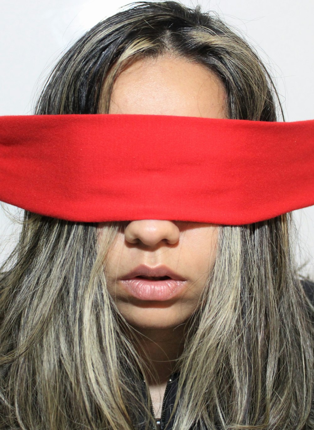 a woman covering her eyes with a red piece of cloth