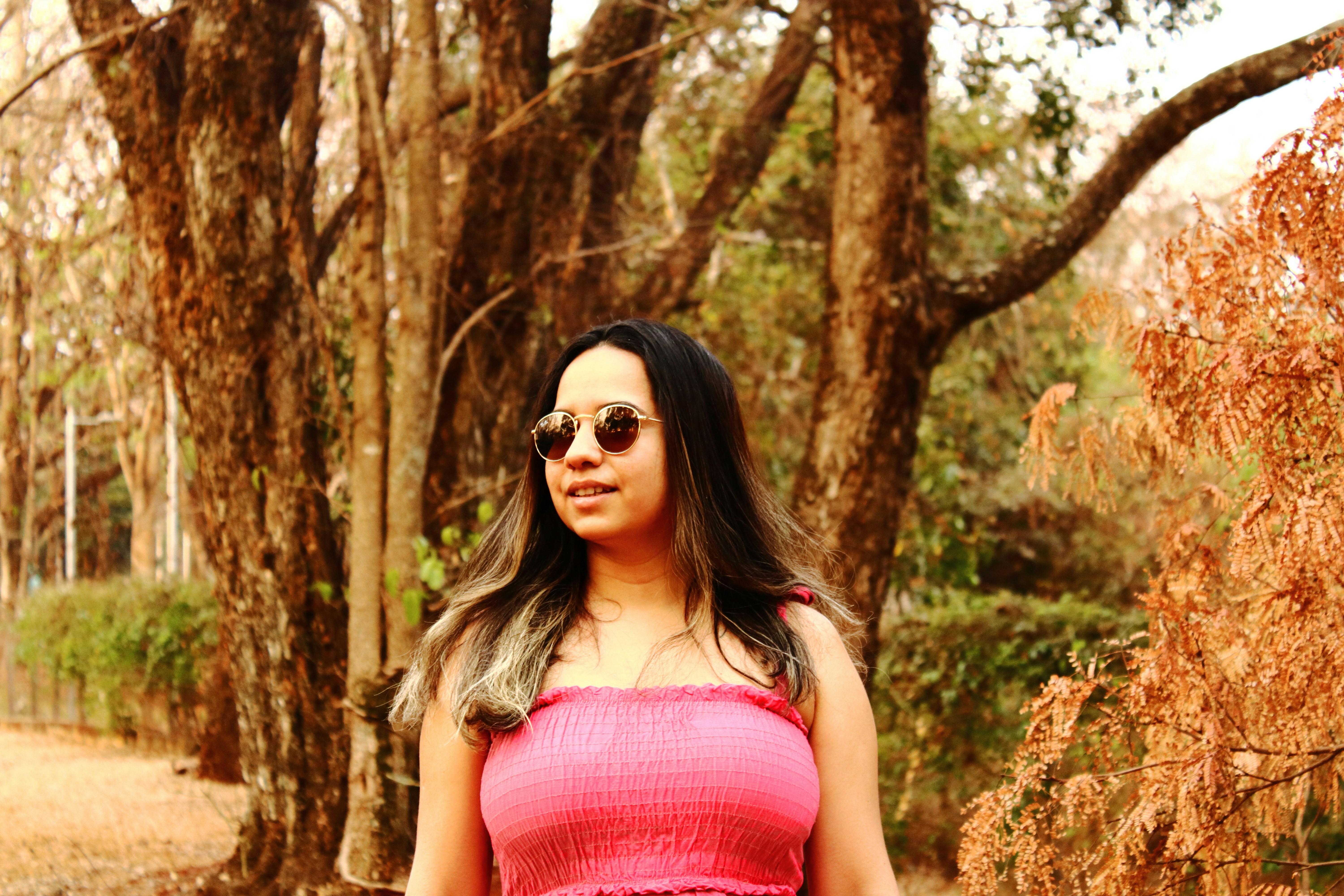 a woman in a pink dress standing in front of trees