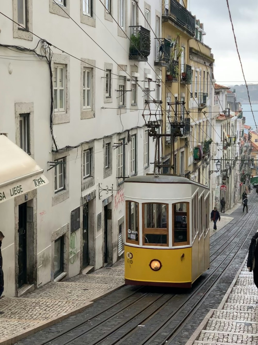 a yellow trolley car traveling down a street next to tall buildings