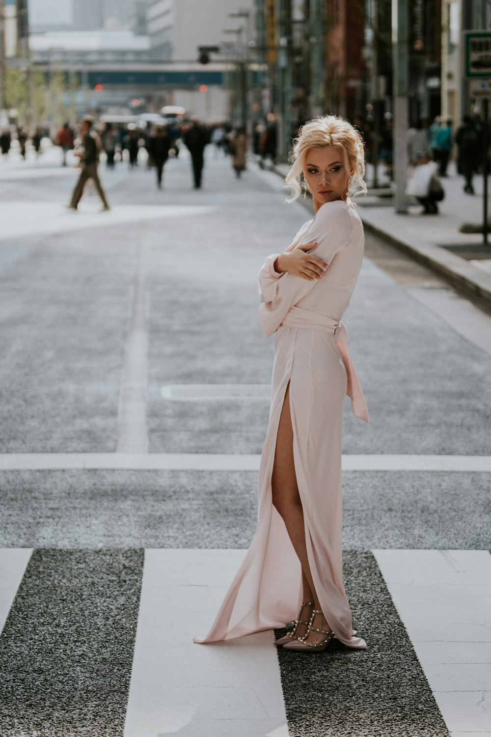 a woman in a pink dress standing on a cross walk