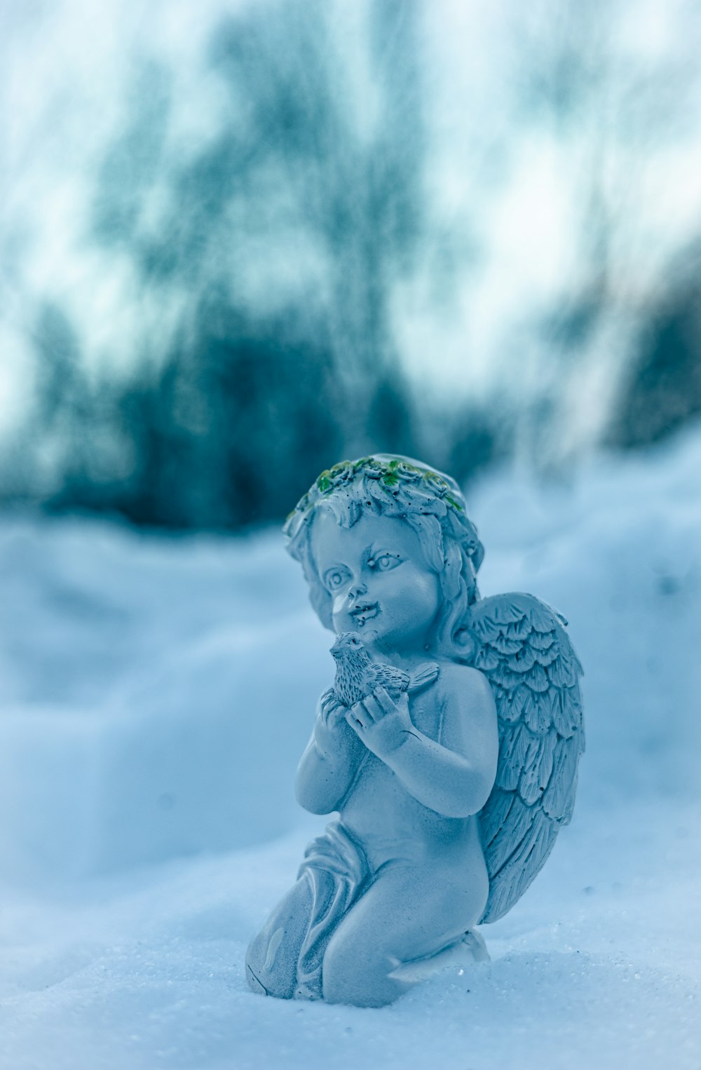 a statue of an angel sitting in the snow