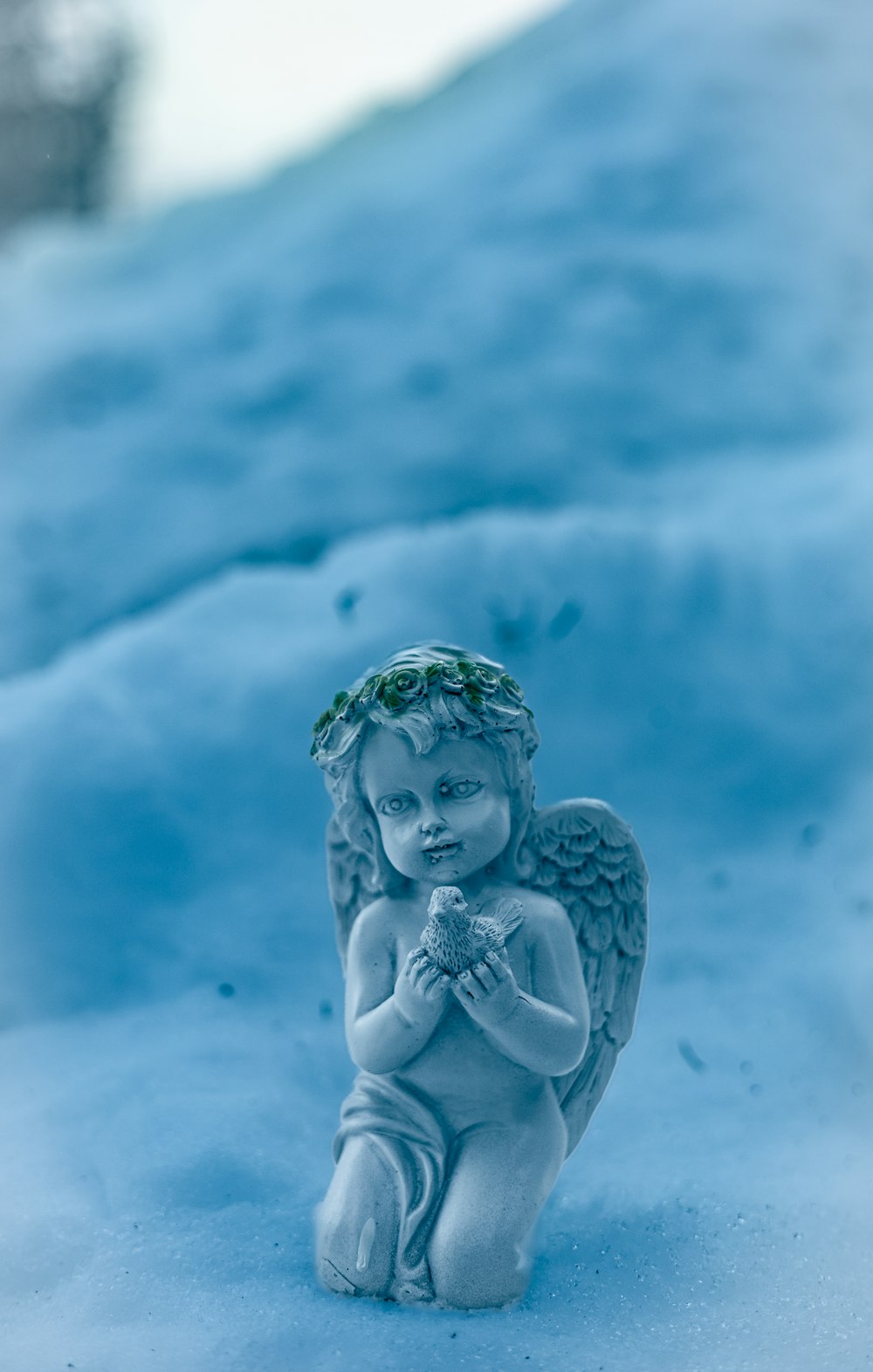 a statue of an angel sitting in the snow