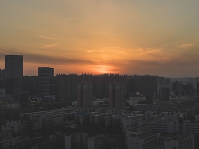 Modern city skyline at sunset with orange hues.