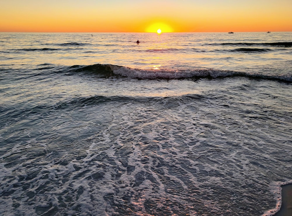 the sun is setting over the ocean waves