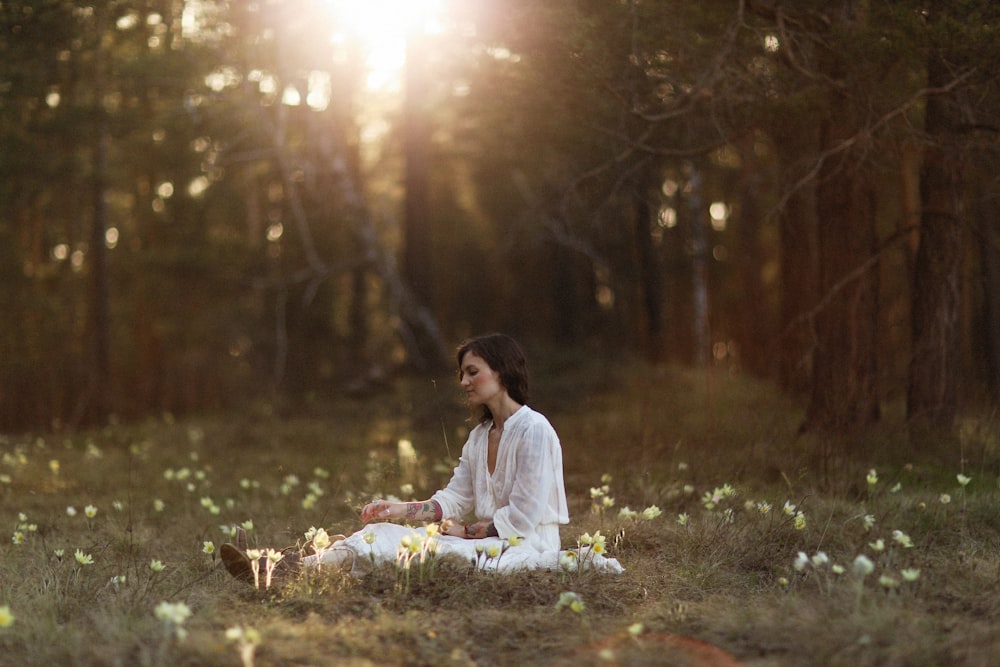 a woman sitting in the middle of a forest