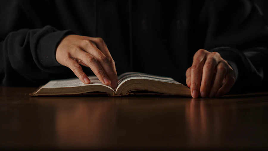 A person sitting at a table quietly reading a Bible