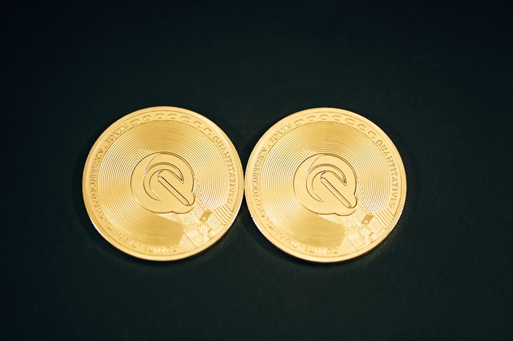 a pair of gold coin sitting on top of a black table