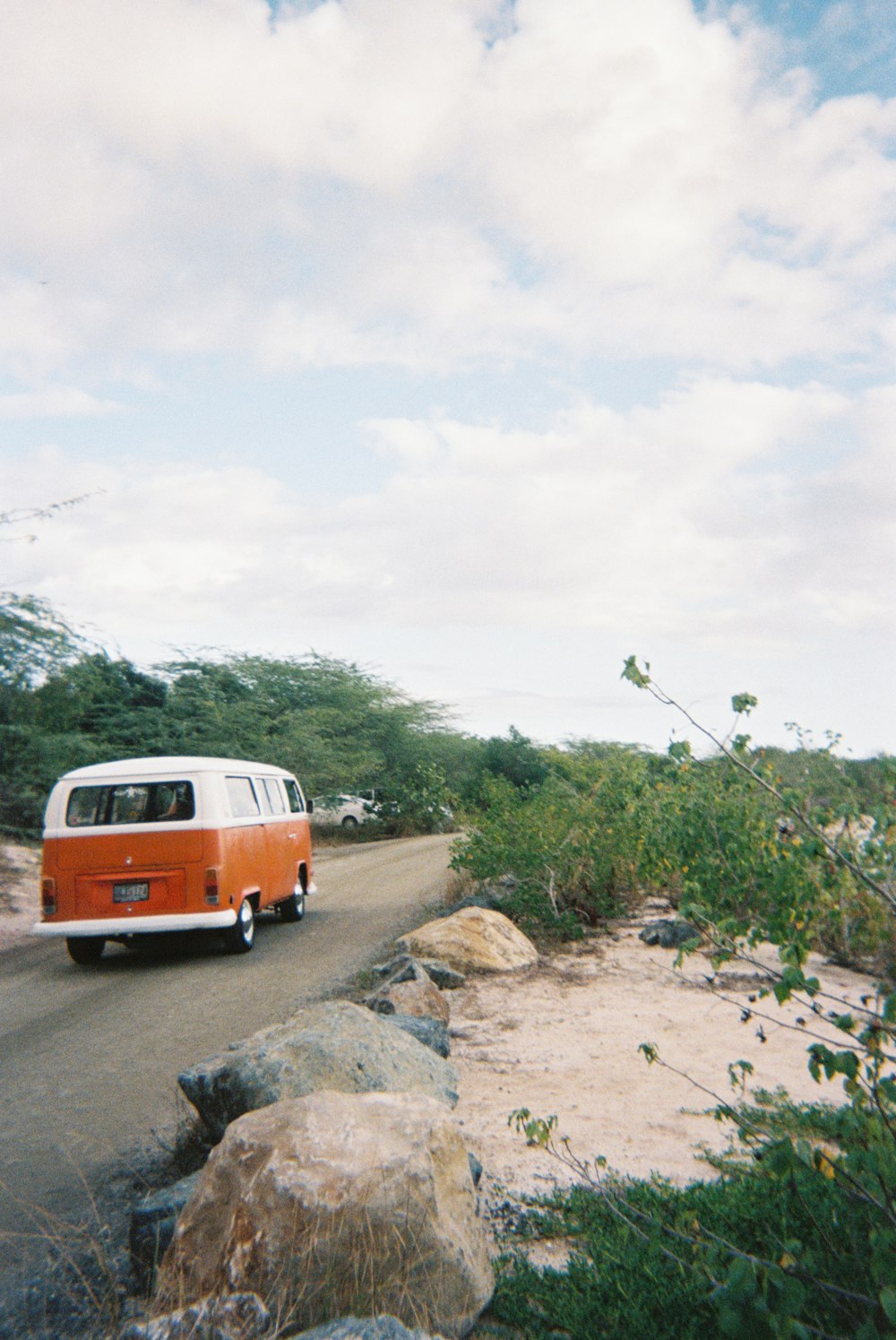 an orange and white van driving down a road