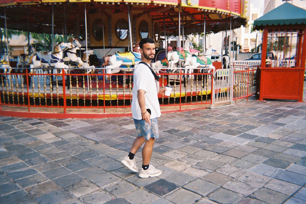 a man is walking in front of a carousel