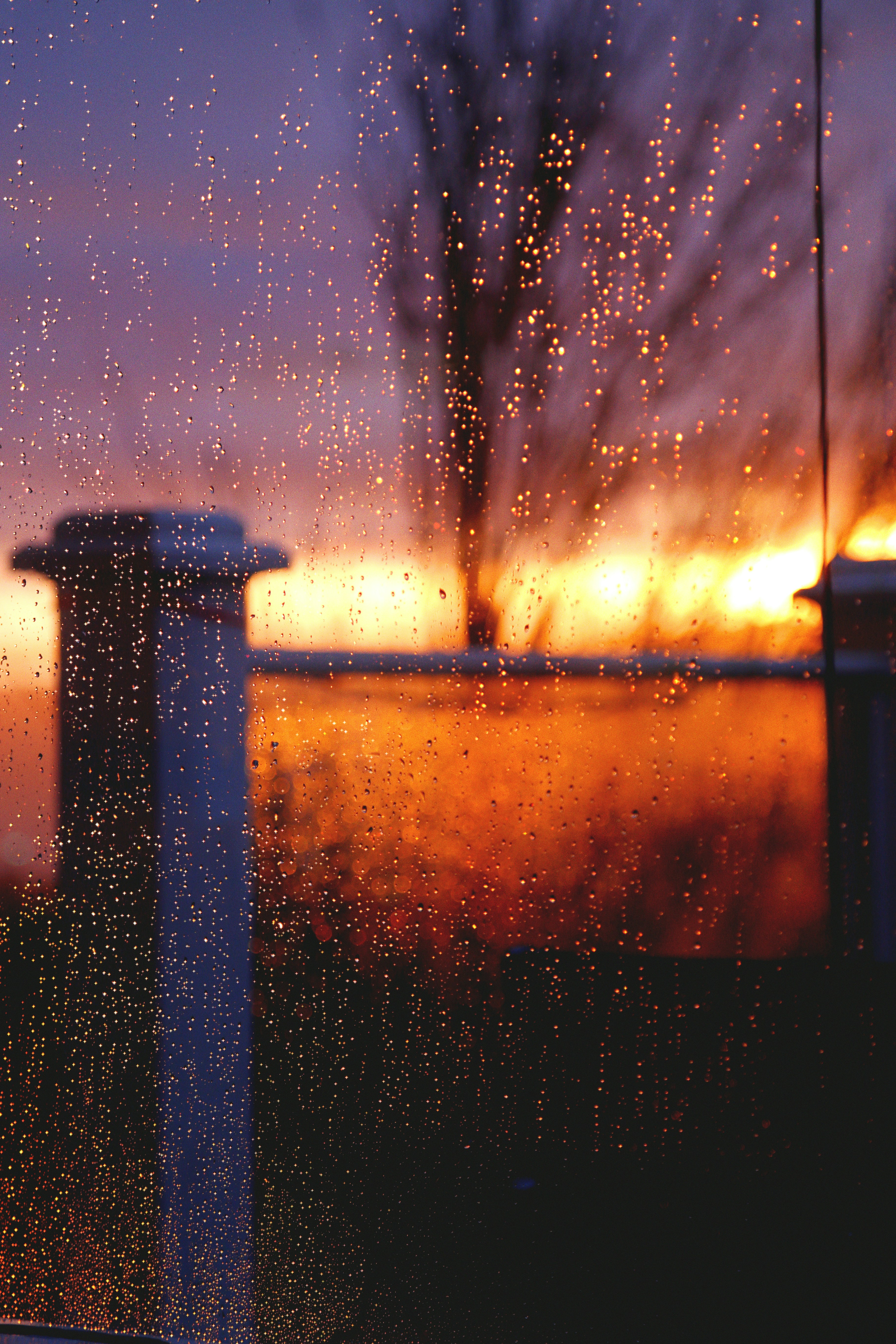 a view of a sunset through a rain covered window
