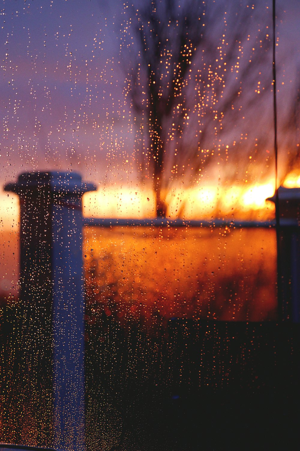 a view of a sunset through a rain covered window