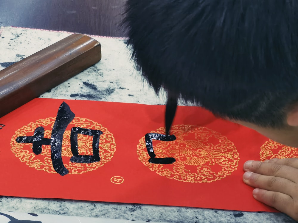 a man is writing on a red paper