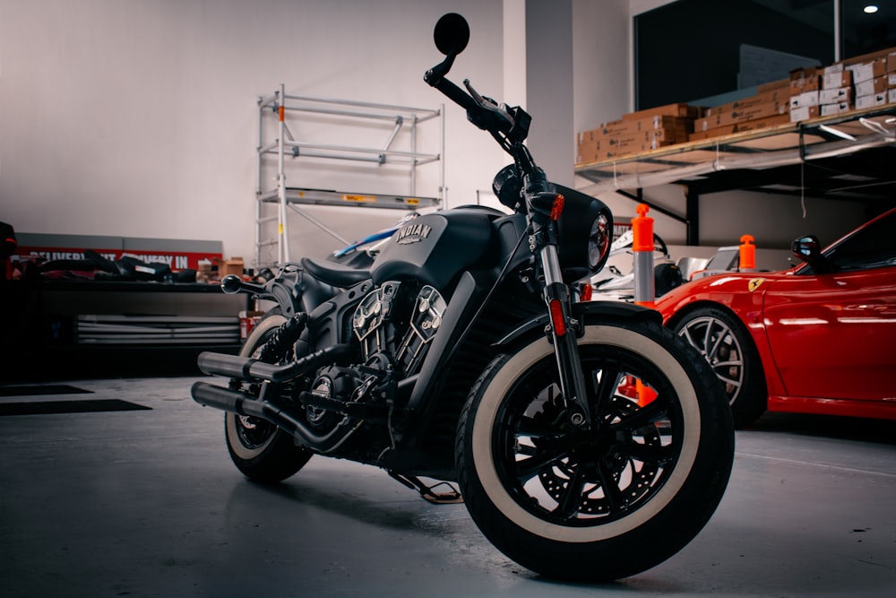 a motorcycle parked in a garage next to a red car