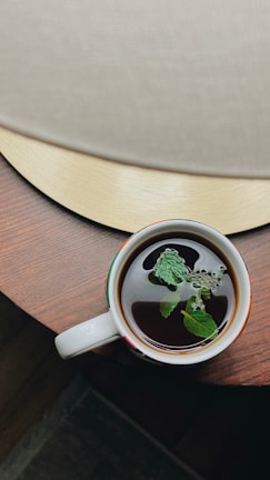 A serene morning scene with a cup of herbal tea beside fresh neem leaves on a wooden table.