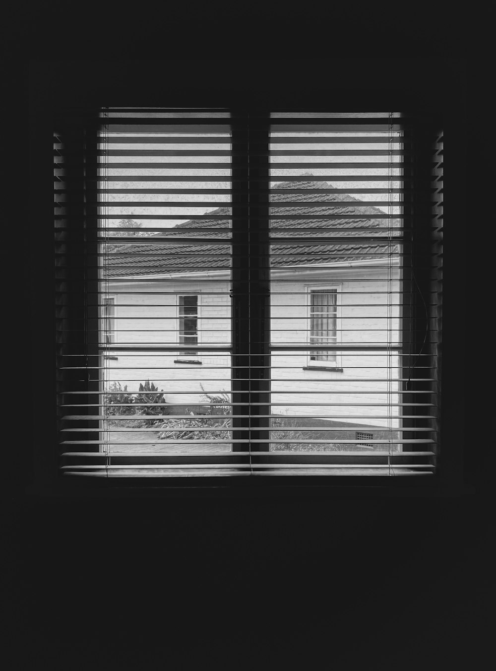 a black and white photo of a window with blinds