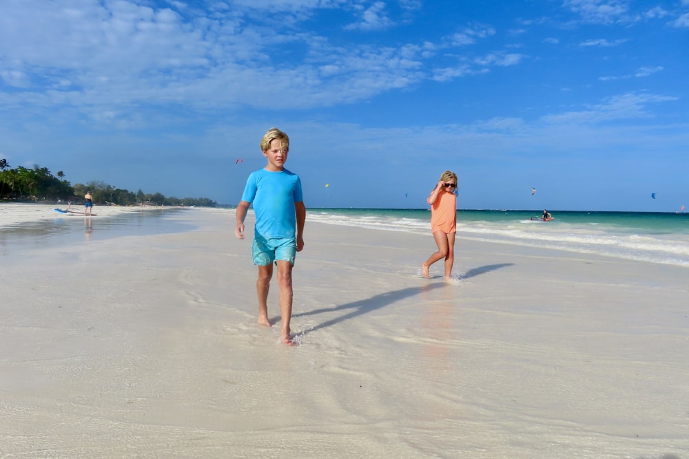 a boy and a girl are walking on the beach