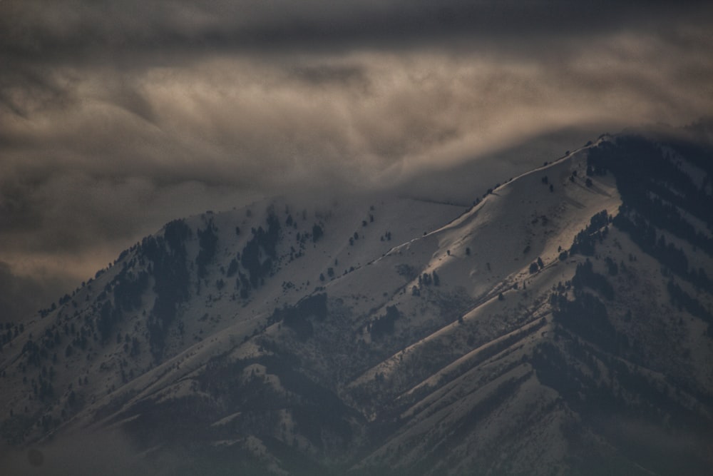 a large mountain covered in snow under a cloudy sky