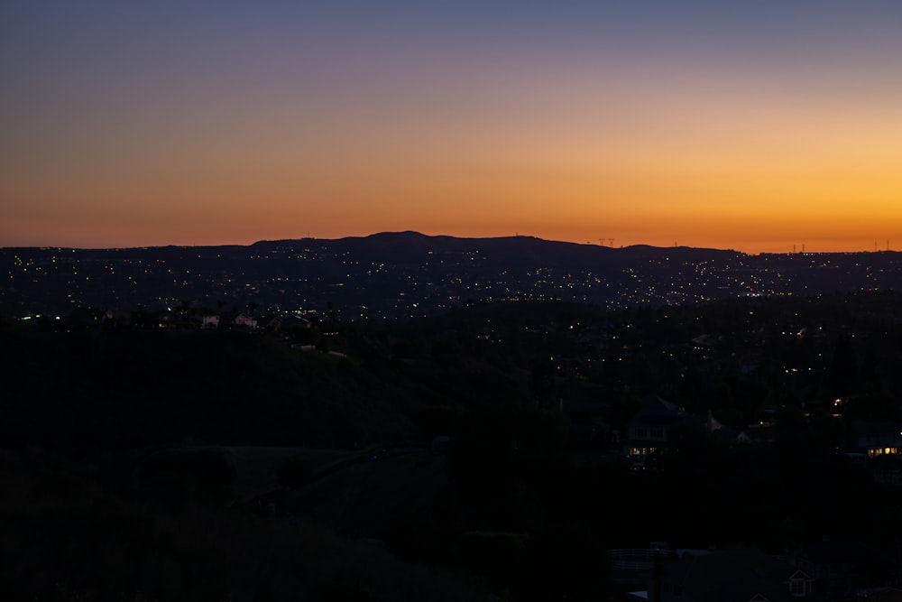 the sun is setting over a city with mountains in the background