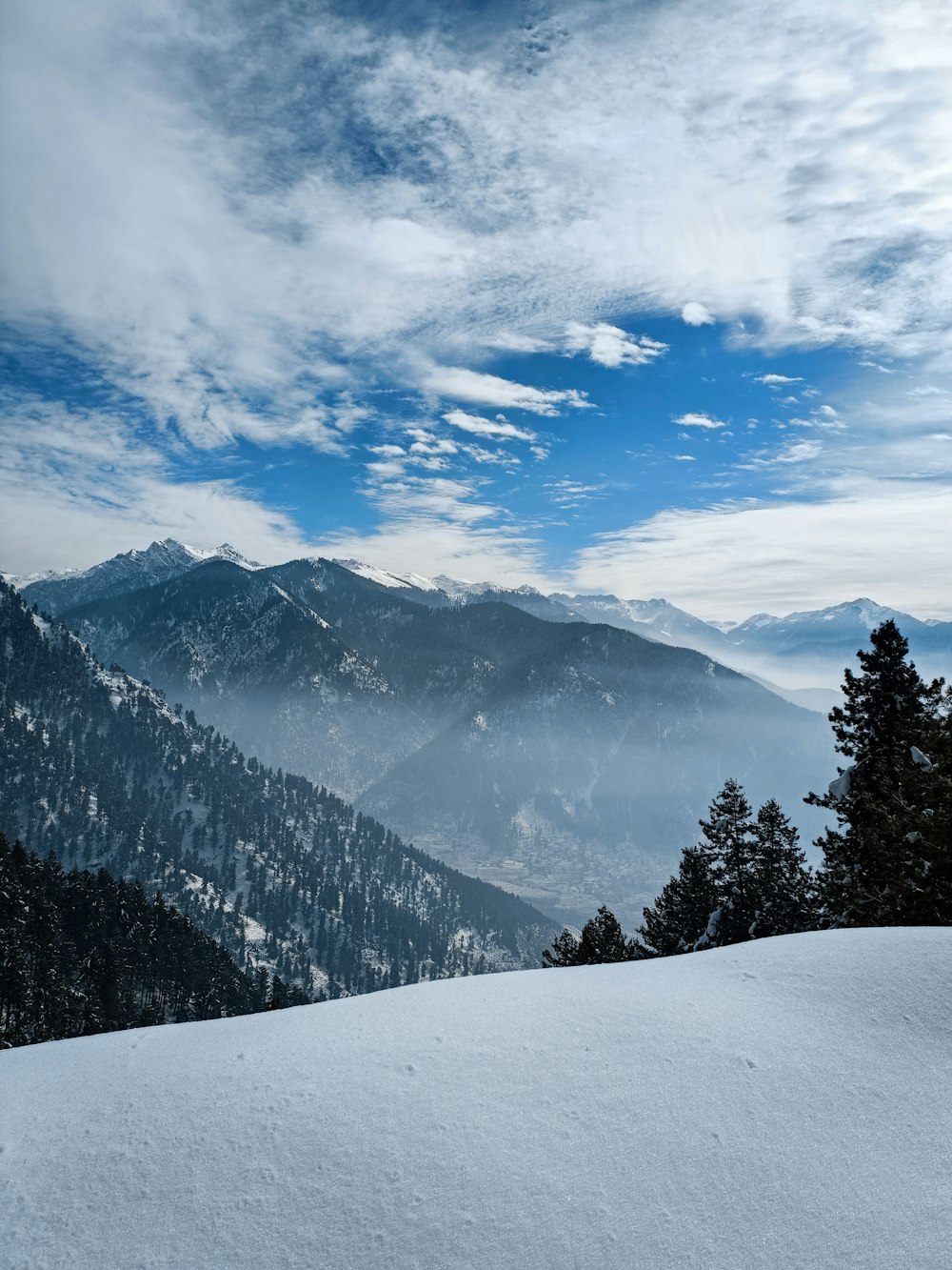 a view of a snowy mountain range with trees