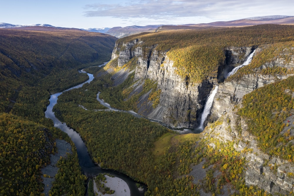 a waterfall with trees on the side of a mountain