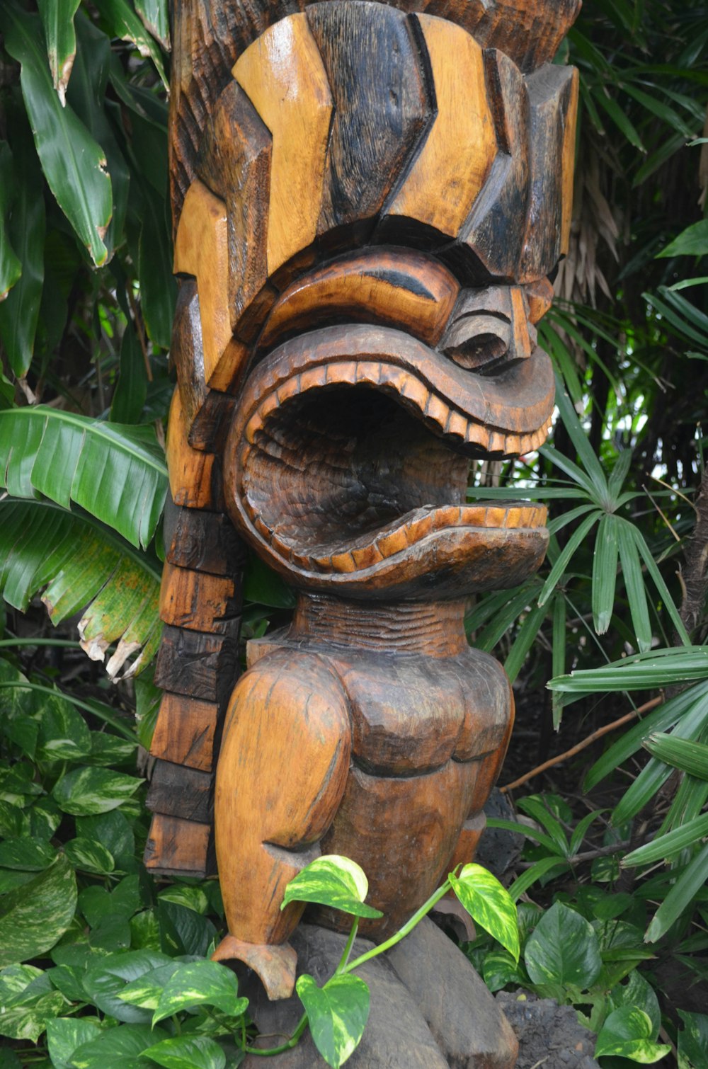 a wooden statue of a frog in a forest