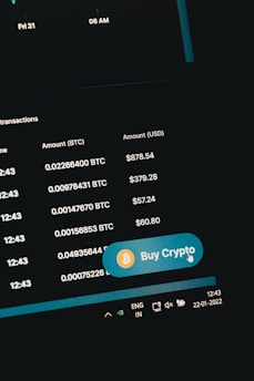 A digital screen displaying cryptocurrency transaction details including Bitcoin amounts and their USD equivalents. A prominent 'Buy Crypto' button with a Bitcoin symbol is visible. The screen shows navigation elements and the date on the system tray is 22-01-2022.