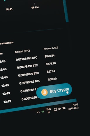 A digital screen displaying cryptocurrency transaction details including Bitcoin amounts and their USD equivalents. A prominent 'Buy Crypto' button with a Bitcoin symbol is visible. The screen shows navigation elements and the date on the system tray is 22-01-2022.