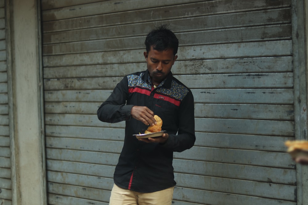 a man holding a plate of food in front of a building