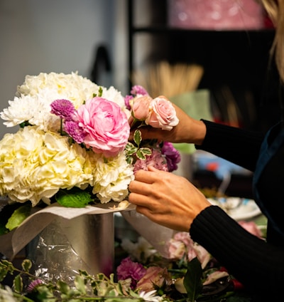 a woman arranging flowers in a vase on a table