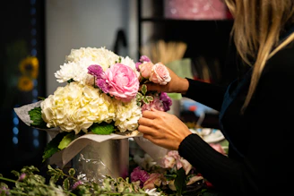 a woman arranging flowers in a vase on a table