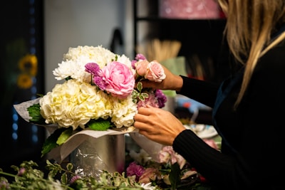 a woman arranging flowers in a vase on a table
