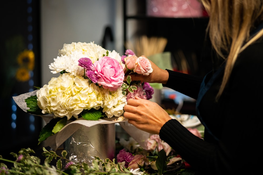 テーブルの上の花瓶に花を並べる女性