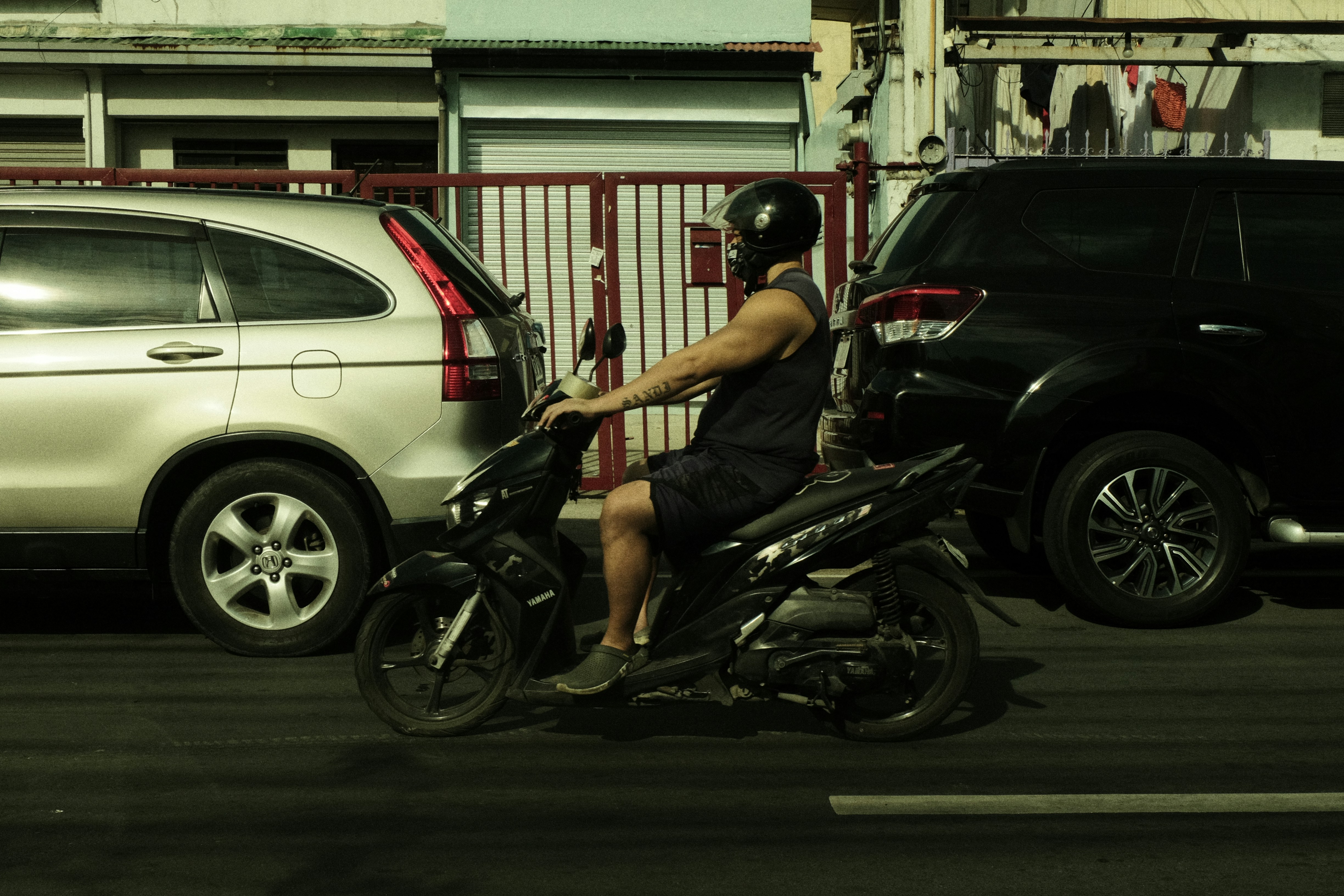 a man riding a motorcycle next to a parked car