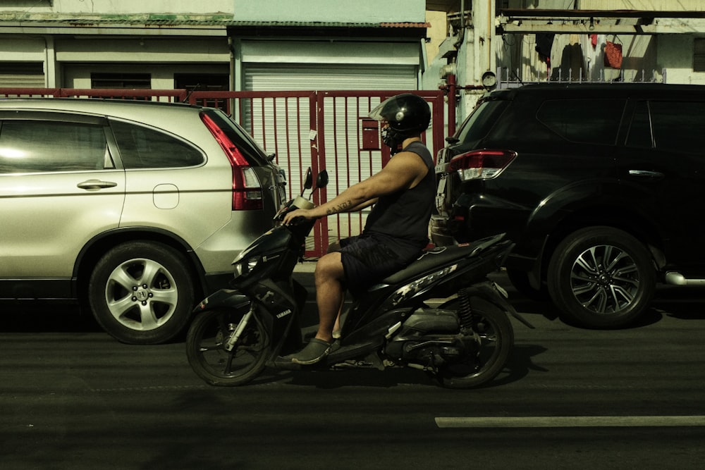 a man riding a motorcycle next to a parked car