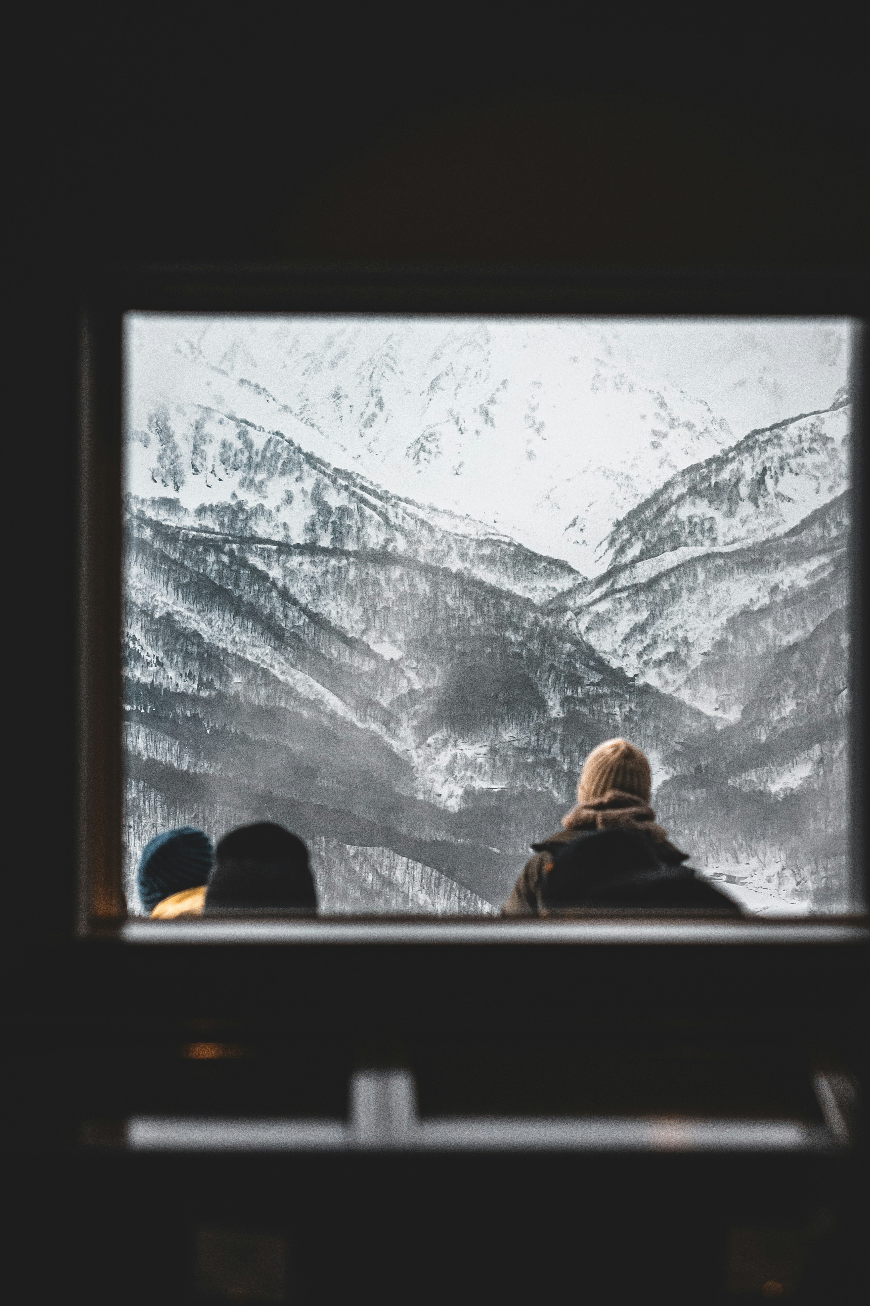 two people looking out a window at a mountain range