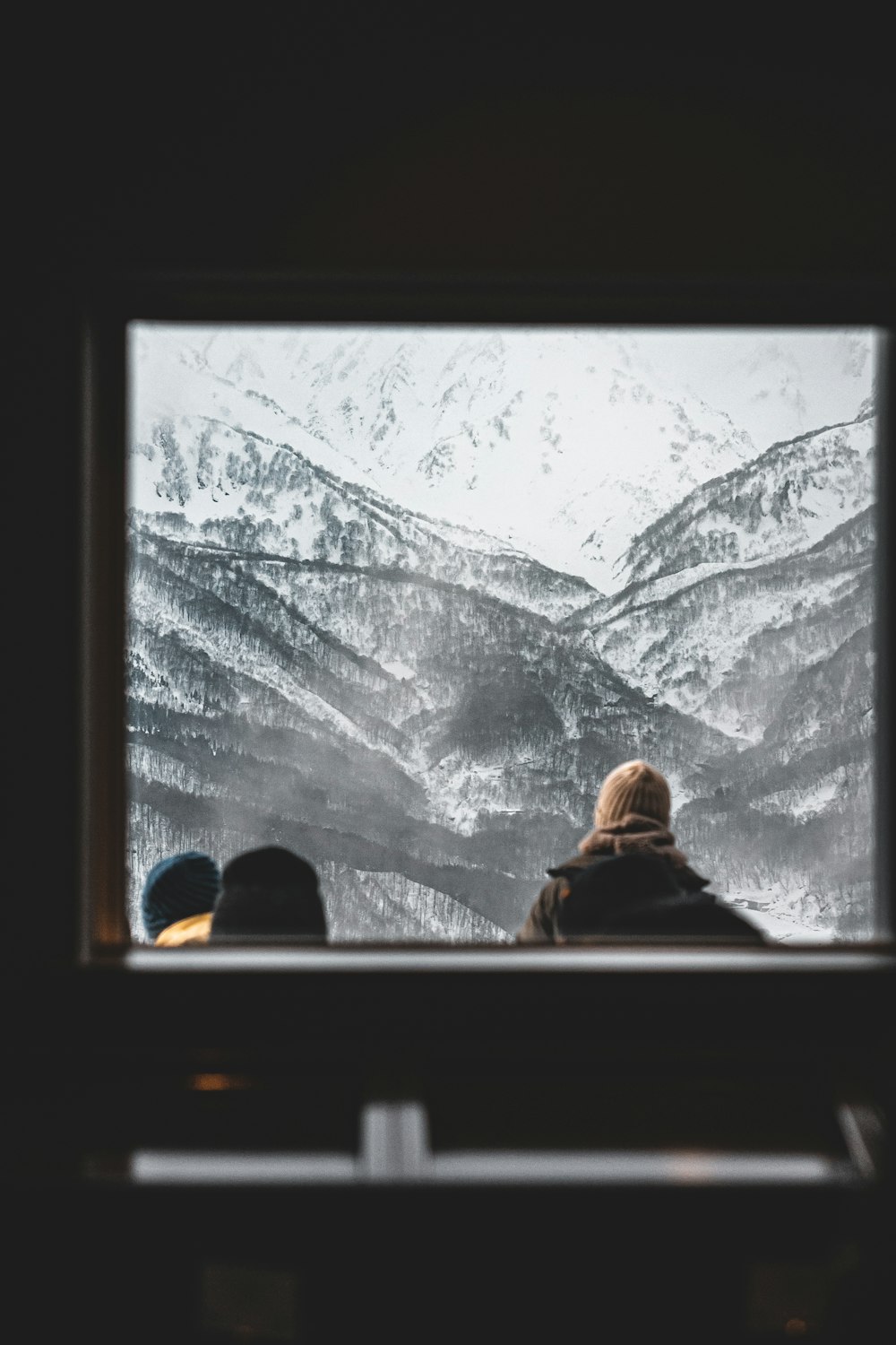 two people looking out a window at a mountain range